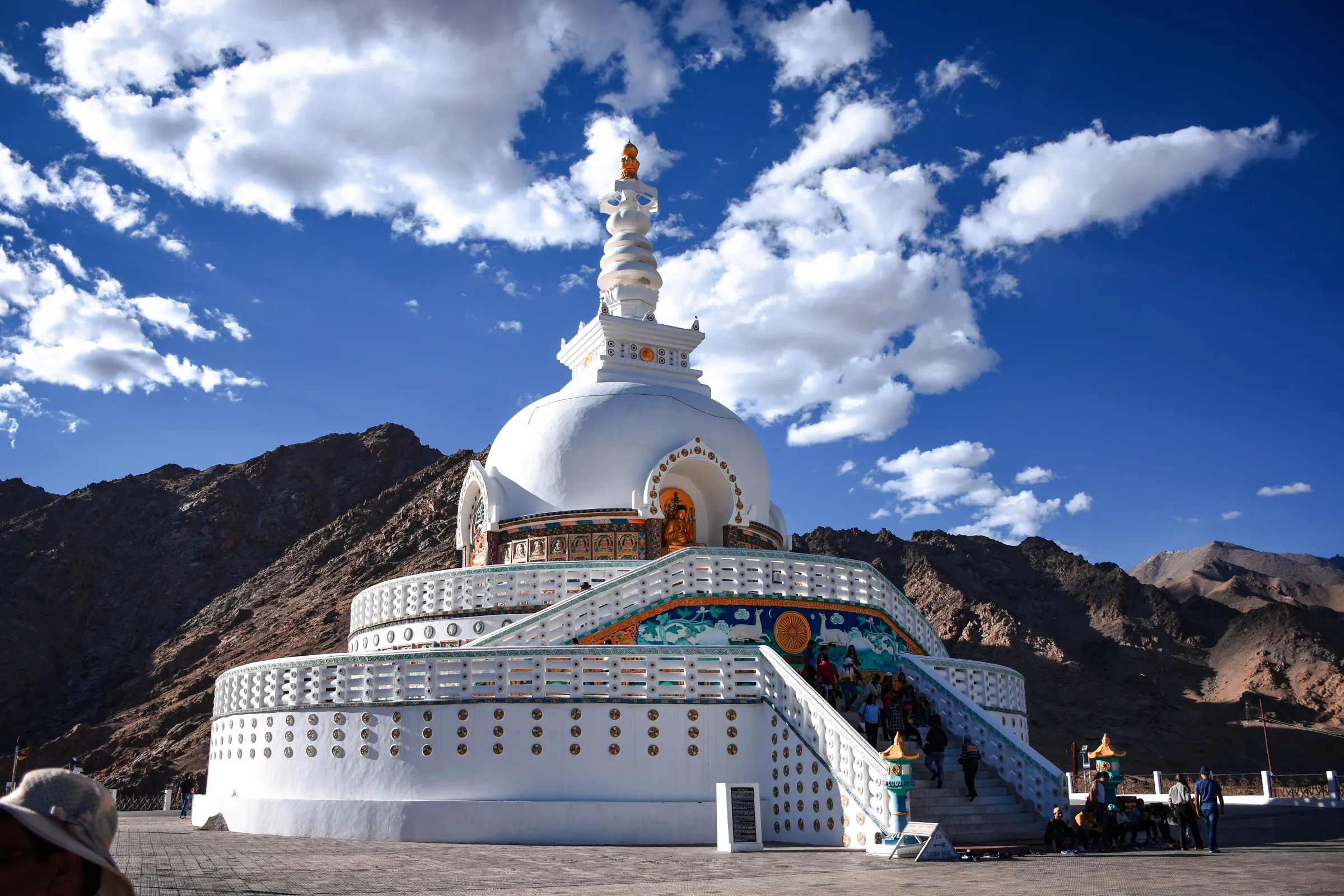 A white Buddhist stupa against rugged mountain peaks