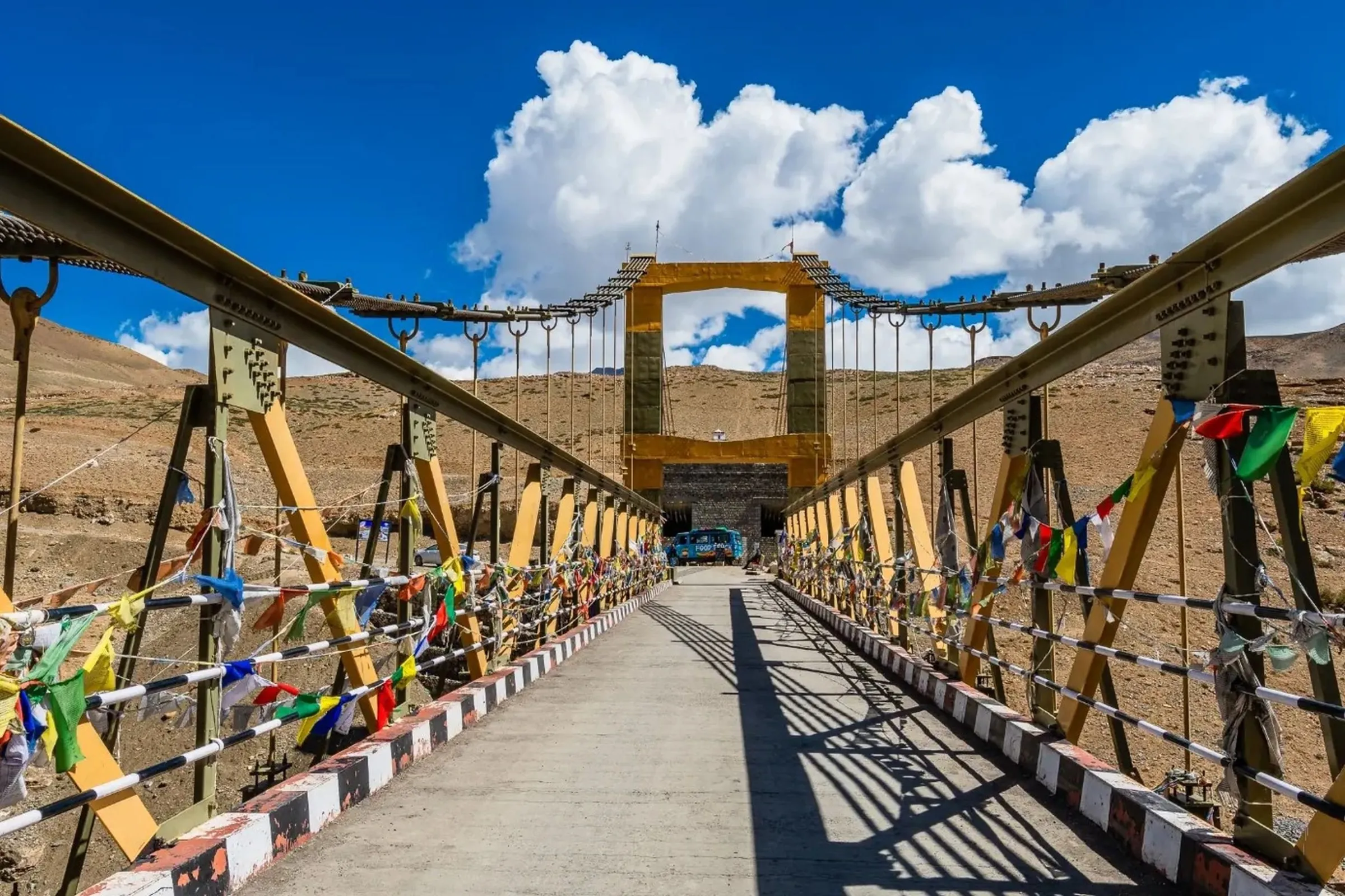 Crossing a bridge beneath bright mountain skies