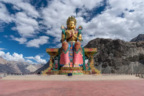 A colourful Buddhist statue framed by mountain views