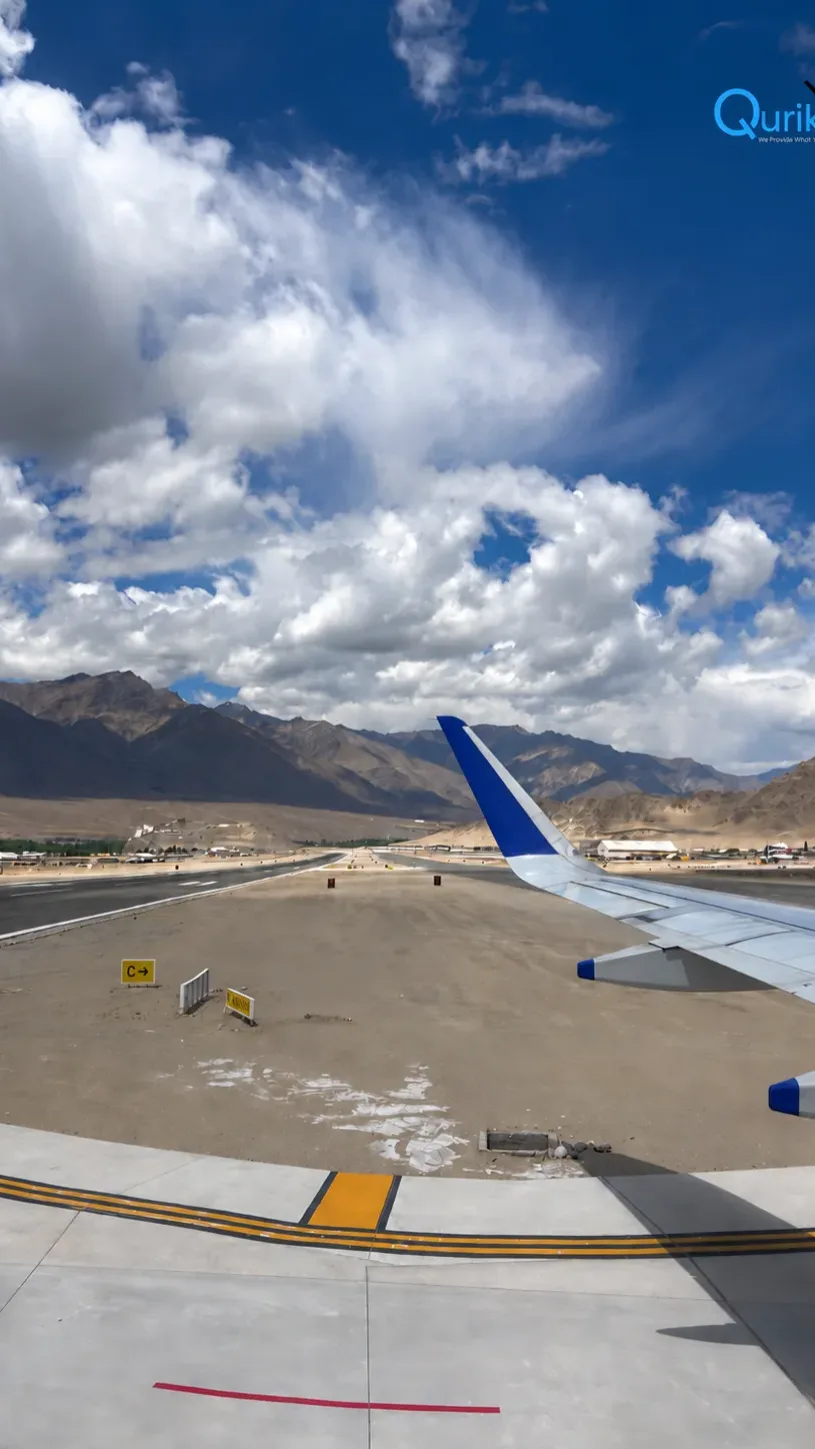 Airplane wing at Leh airport surrounded by mountains under dramatic clouds