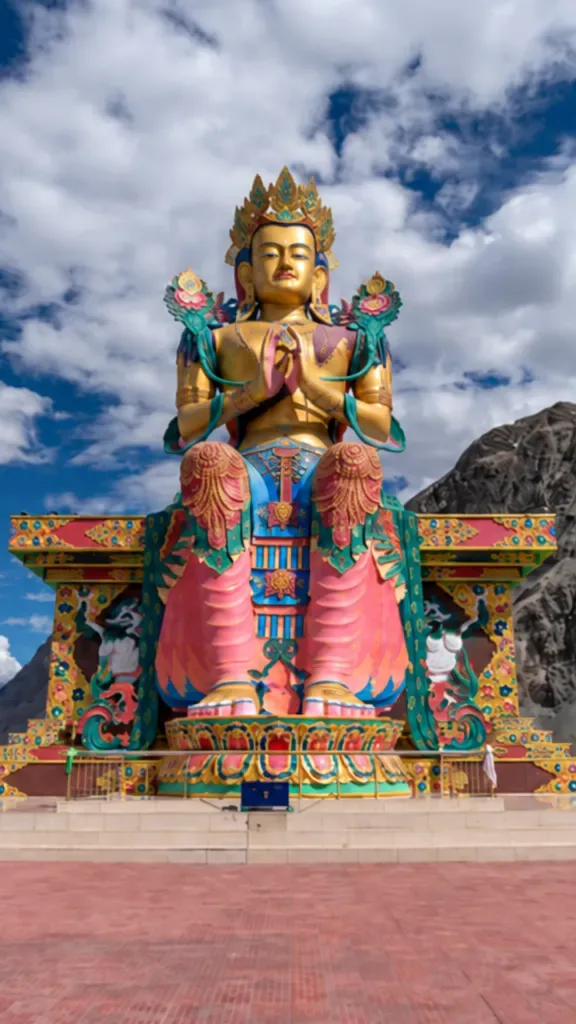 Large colorful Maitreya Buddha statue overlooking mountains in Nubra Valley Ladakh